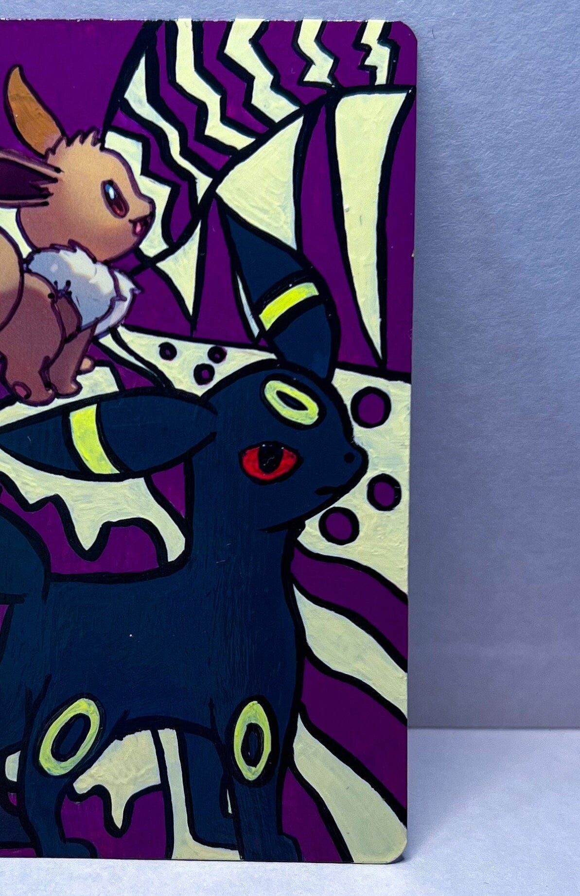 Eevee Original Pokemon Card Hand Painted with beige and purple with black line art featuring a proud standing Umbreon. Acrylic Paint with high gloss varnish finish sleeved and hard sleeved